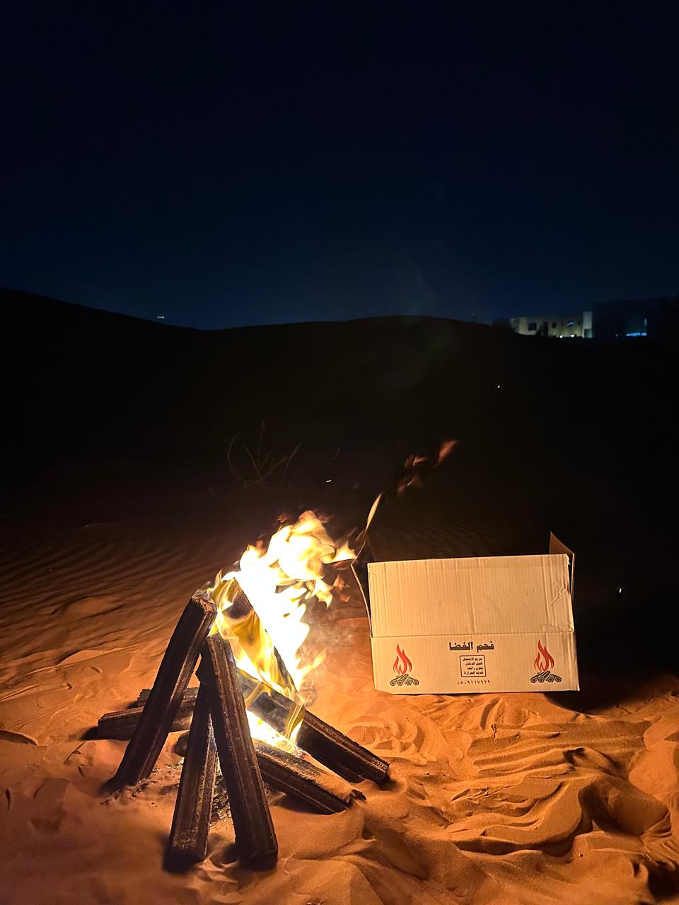 Fire pit with a box labeled 'Petrol' on sand at night
